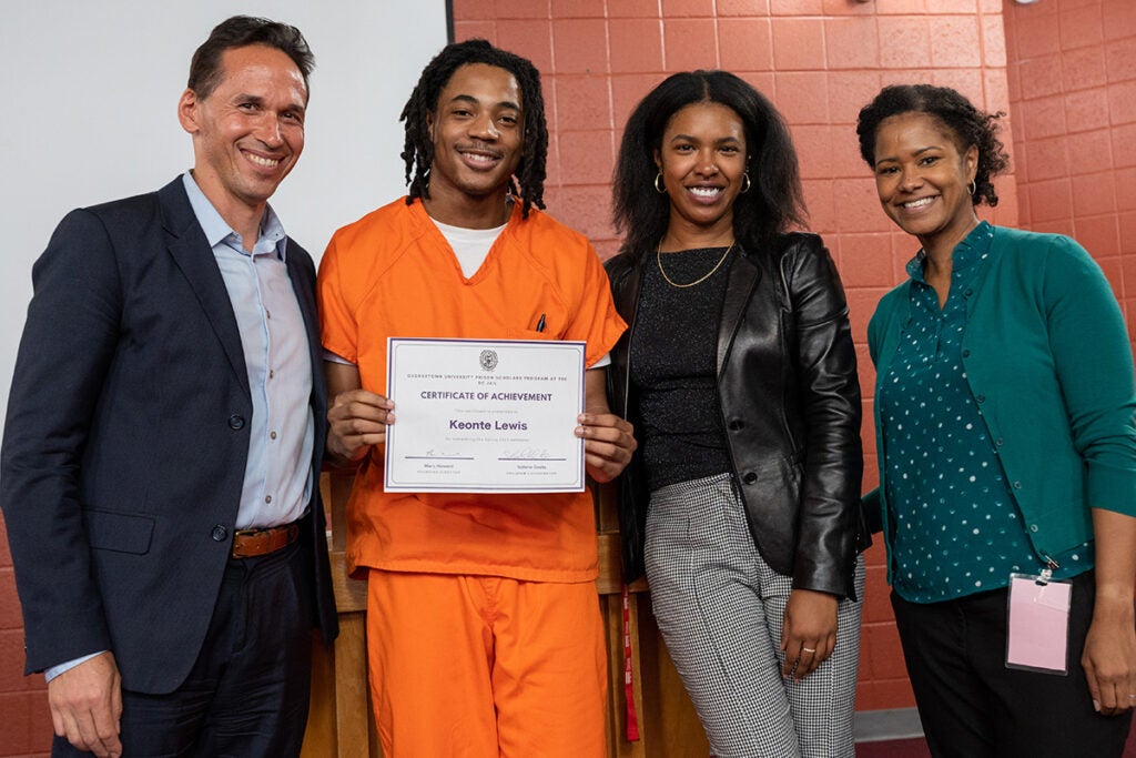 Keonte Lewis holds a certificate and poses for a photo with three Georgetown staff members.