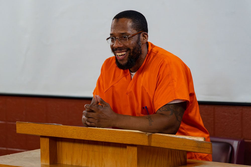 Georgetown Prison Scholar Colie Long smiles from behind a podium.