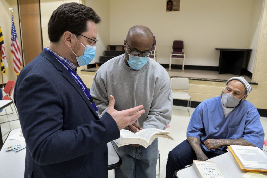 A professor speaks to two incarcerated students.