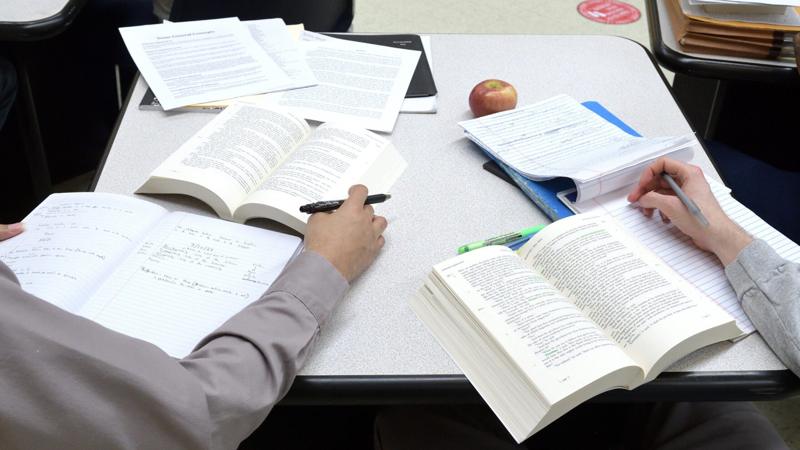 Two students' hands on open books.