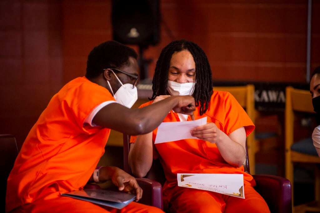 Two incarcerated students look at a paper together.