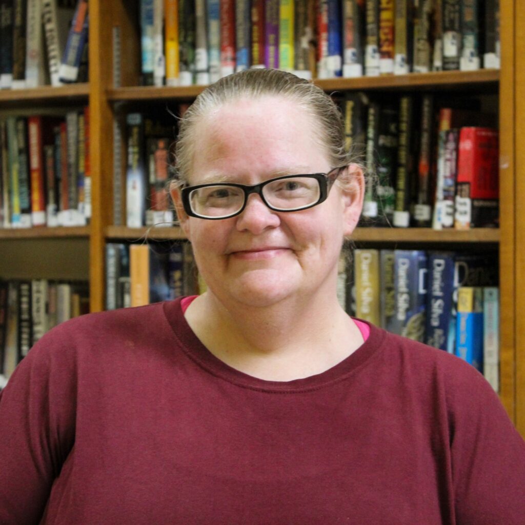 Amy McNamara in front of a prison library bookshelf.